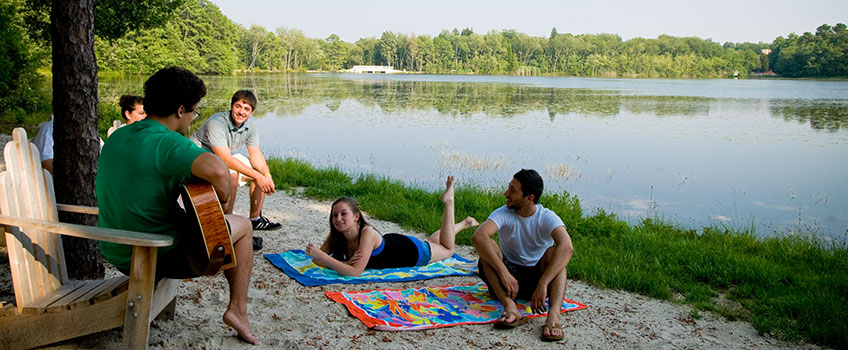 students on sand by lake