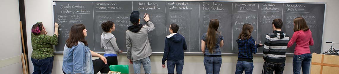 Students conjugating verbs on chalkboard