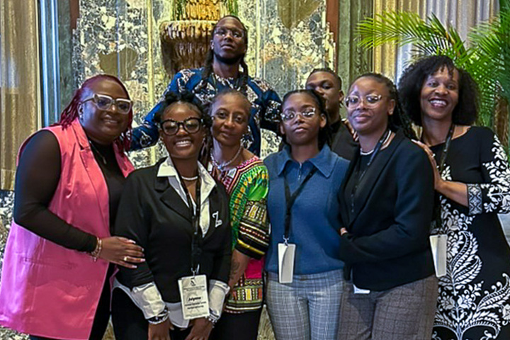 Africana Studies students and faculty members at a national conference post in a ballroom with gold draping in the background