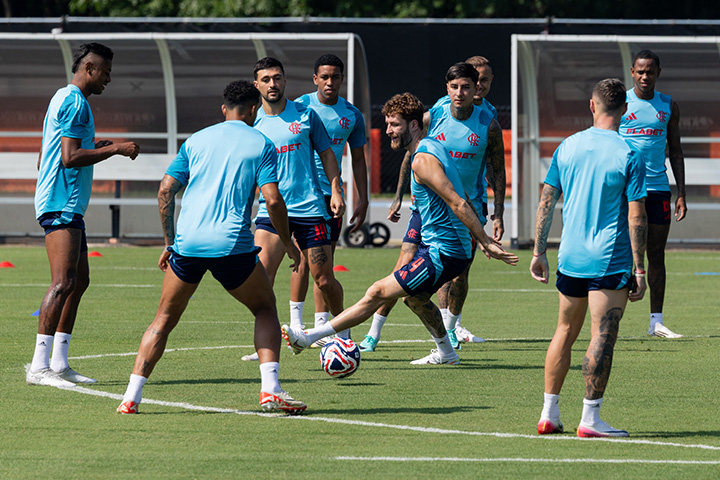 Members of CR Flamengo football team wear light blue practice jerseys while dribbling a soccer ball on a green field