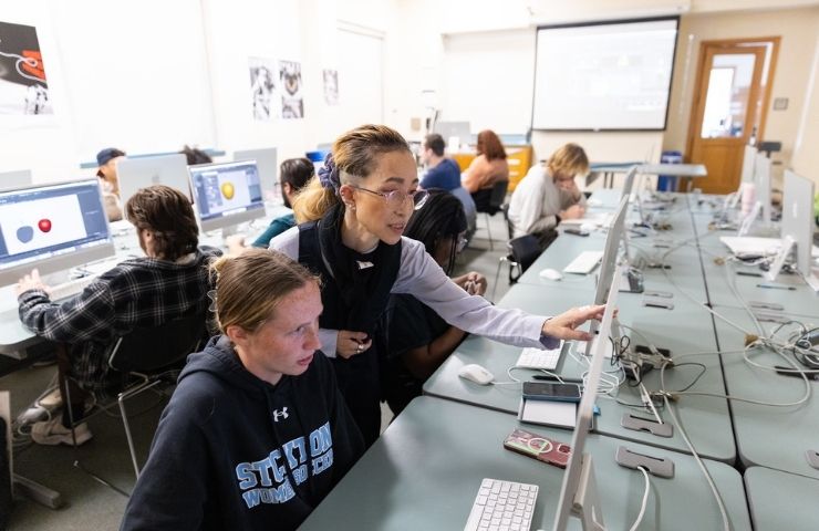Student working in the visual arts computer lab with faculty
