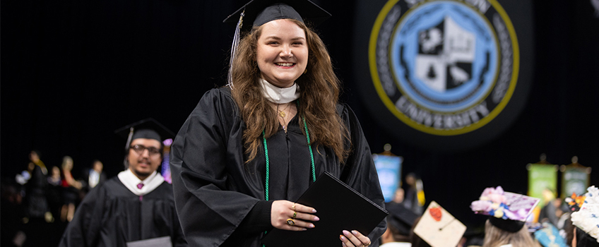 A student wearing a green honor cord during Commencement