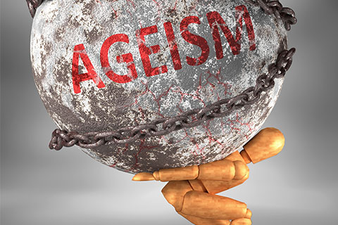 Stock image of a doll holding a boulder with the word "Ageism"