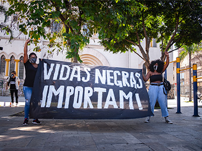 Protestors in Brazil, holding a flag that says "Black Lives Matter" in Portuguese