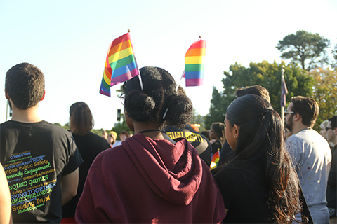 Student attending a pride flag raising in 2023 with rainbow flags in her hair