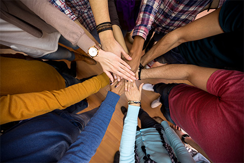 A stock image of team members holding their hands in the center