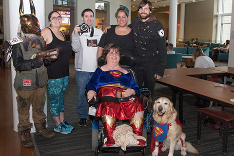 Lydia Fecteau (Superwoman) during a Halloween event with her service dog and friends in the Campus Center