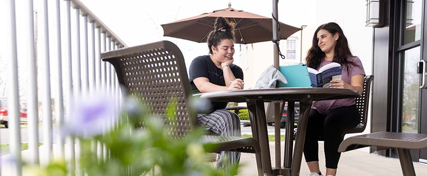 Two women at an outdoor table conversing