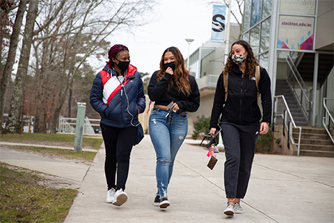 Spring Scene from 2021 - three students, masked, walking down the breezeway near K-wing
