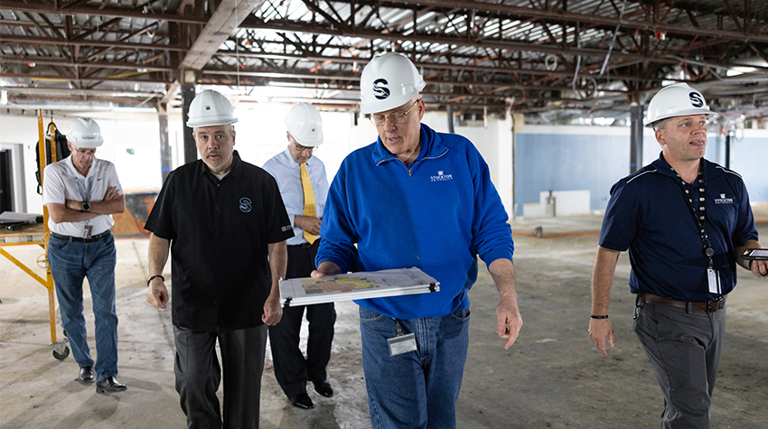 Staff members with hard hats walking through the library while it's under construction