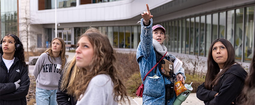 Stockton senior Breanna Hawkins, points out some birds on campus to a group of middle schoolers who attended her Tween Tech workshop. Hawkins, of Marshall, Michigan, is the president of Stockton's Birding Club, and she showed the students how to use the Merlin Bird ID app to identify birdsong on their phones.