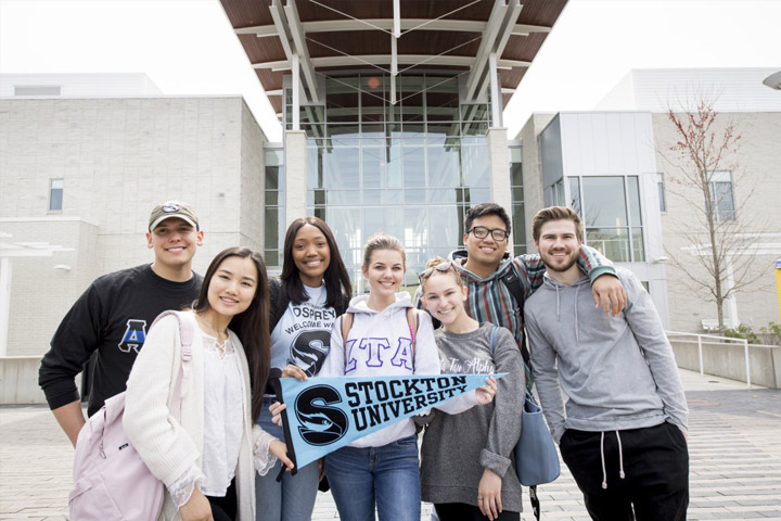 students standing on the Stockton Sign in the Academic Quad