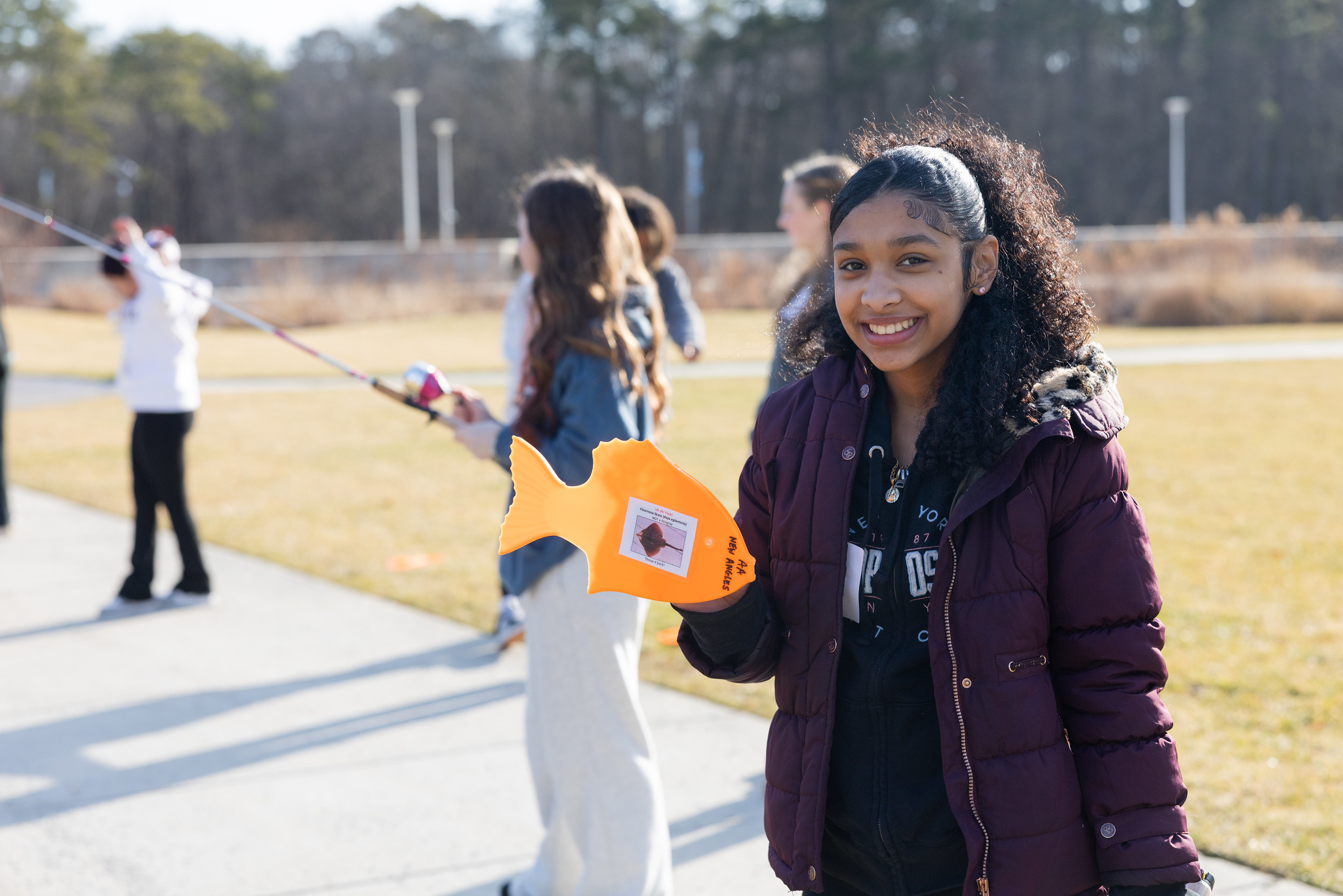 girl holding fishing pole outside