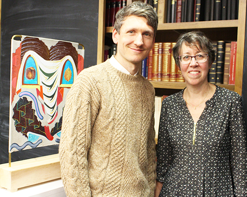man and woman standing in front of books and painting