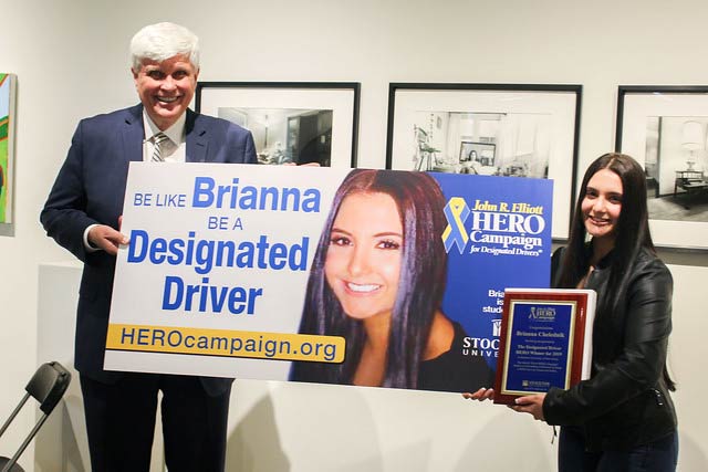 2019 Hero of the Year Brianna Chelednik, a Stockton University student from Egg Harbor Township, with Bill Elliott, founder of the HERO Campaign, and a mockup of the billboard that will promote the HERO Campaign’s designated driver initiative.