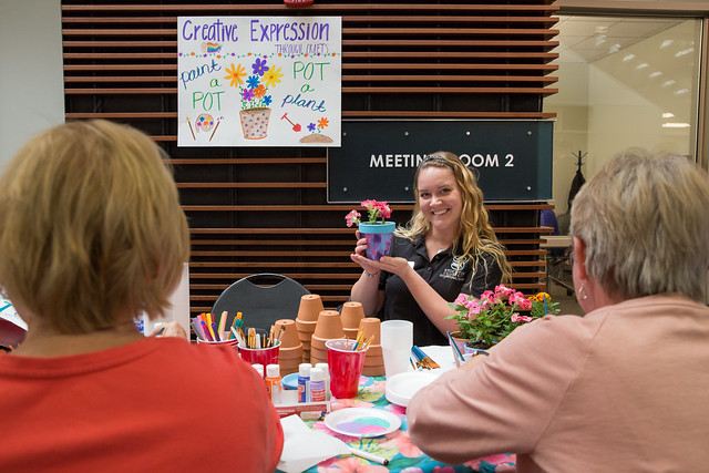 girl teaching seniors how to paint flower posts