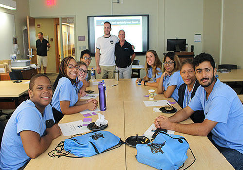 group of students smiling while sitting at table 