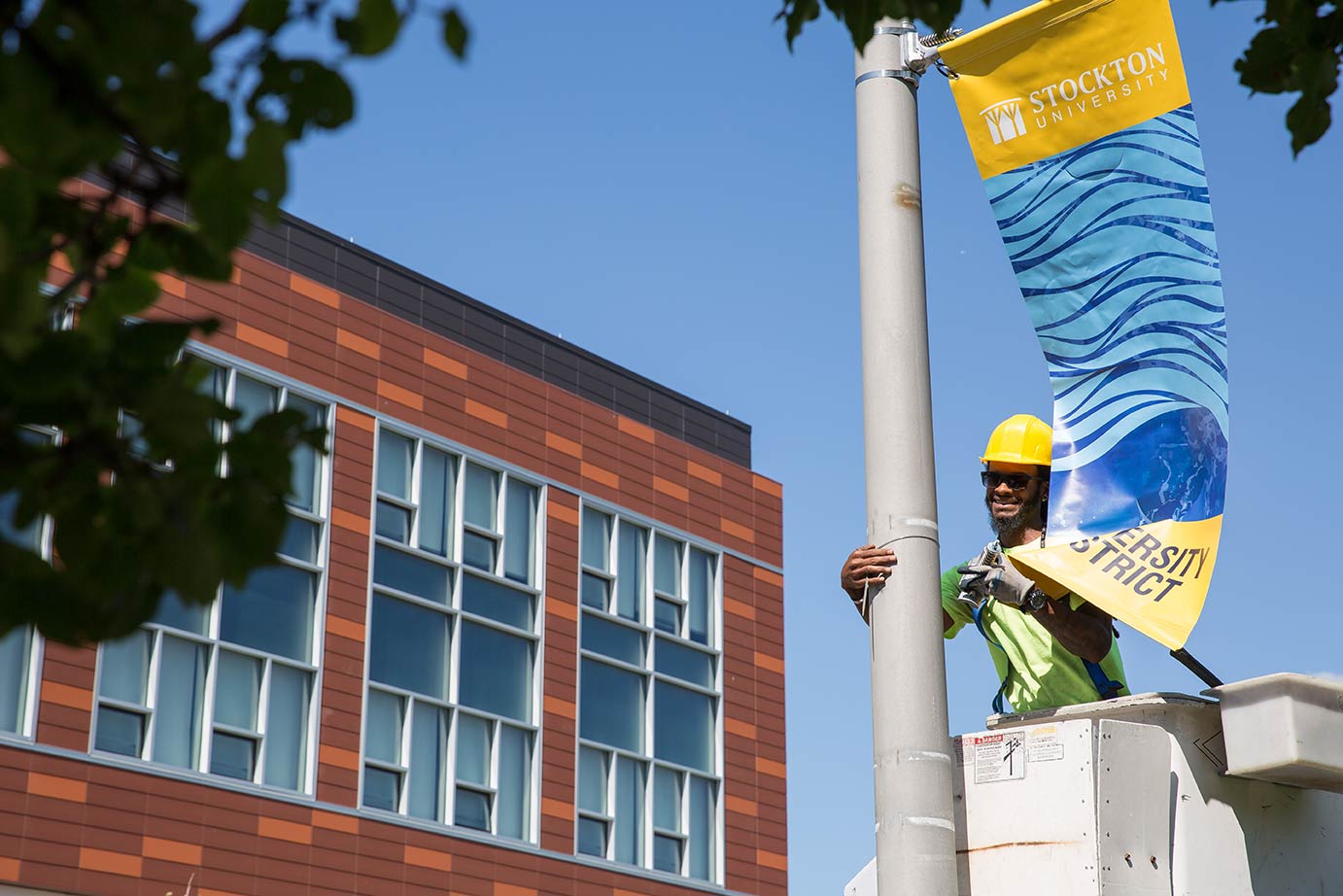 man putting banner on pole 