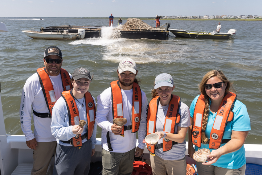 people holding oysters on a boat