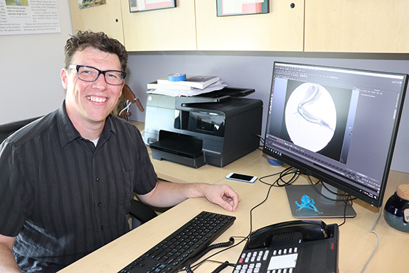 Matthew Bonnan, professor of Biology, demonstrates the Autodesk Maya animation software at his desk.