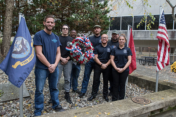 group of men and women smiling around wreath