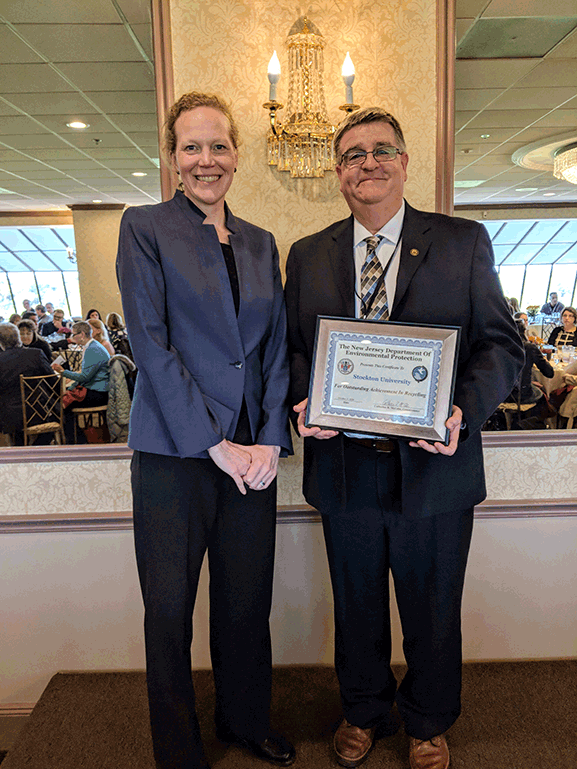 man holding plaque next woman smiling