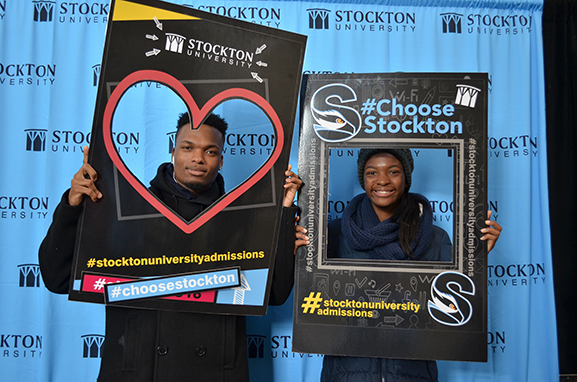 male and female students smiling holding selfie frames