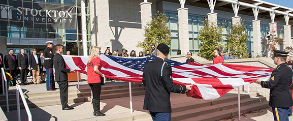 men and women holding large American flag