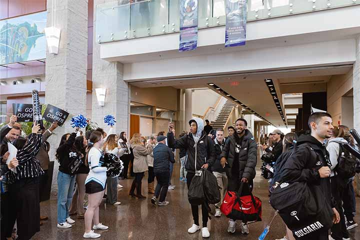 Members of the basketball team walk through a crowd of cheering supporters in the Campus Center
