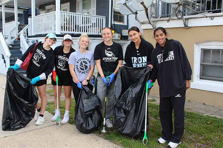 Five members of the field hockey team with trash bags and track pickers