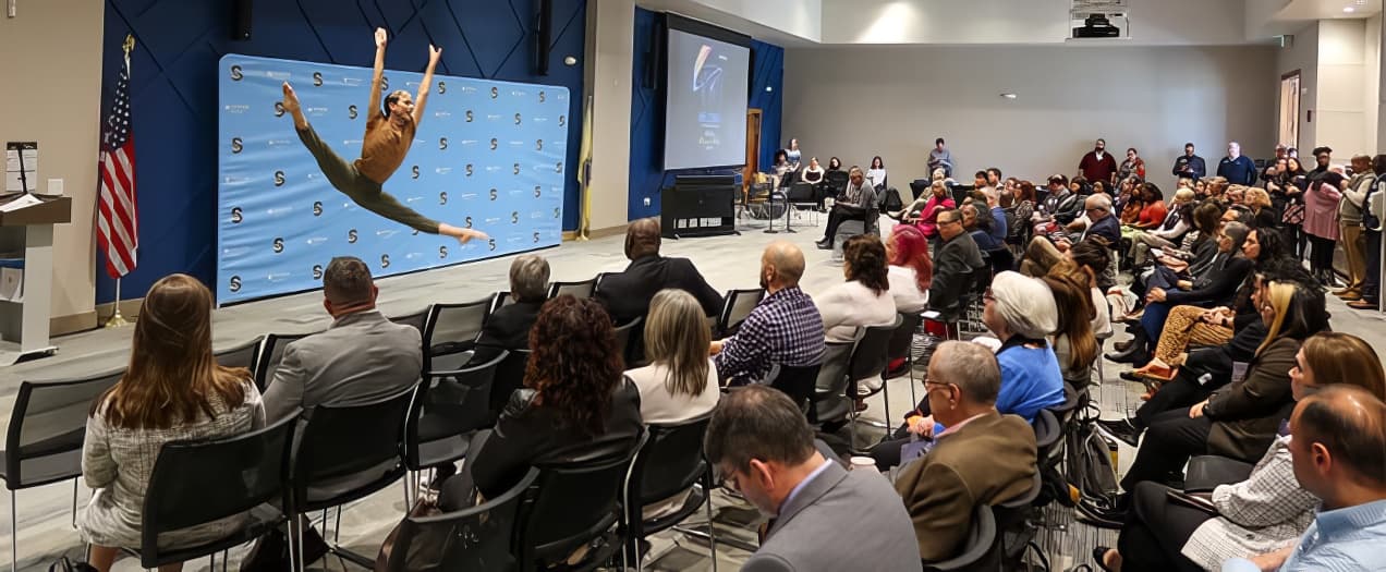 A crowd watches as a dancer leaps into the air in the Fannie Lou Hamer Event Room