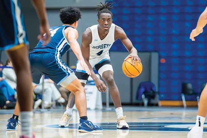 DJ Campbell in white basketball uniform dribbling a basketball in the Sports Center