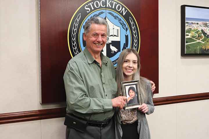 Alex Kaganzev and Victoria DiCicco hold a framed photo of Seeta Voorakkara