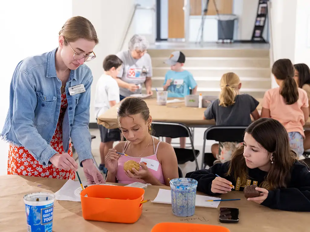 Stockton University instructor assisting children with an art project during a community workshop.