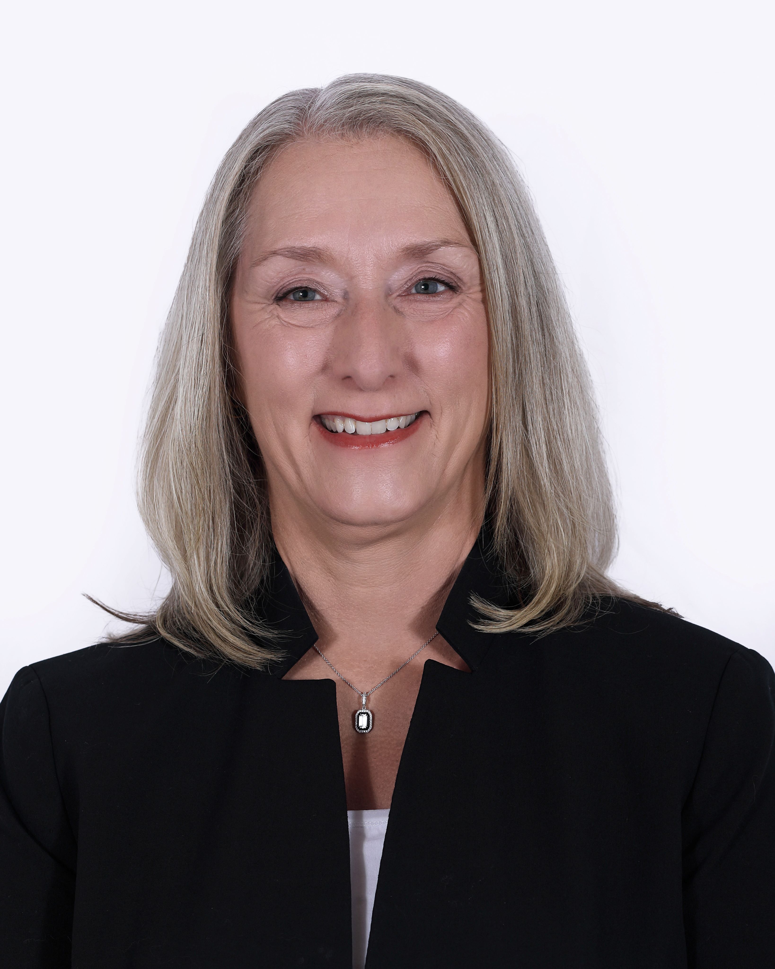Dr. Marty Wygmans with a long, gray bob, a black blazer, white shirt, and necklace