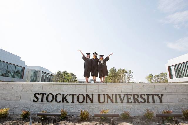 Girls standing on stone wall in graduation gowns